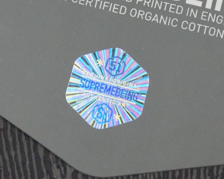 Supreme Being Swing Tag with close up of Holographic Foil